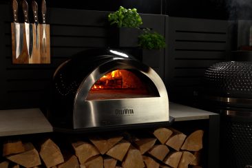 wood fired pizza oven on storage cabinet in outdoor kitchen
