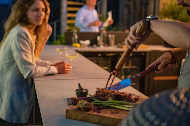 person carving meat on cabinet worktop in grillo outdoor kitchen