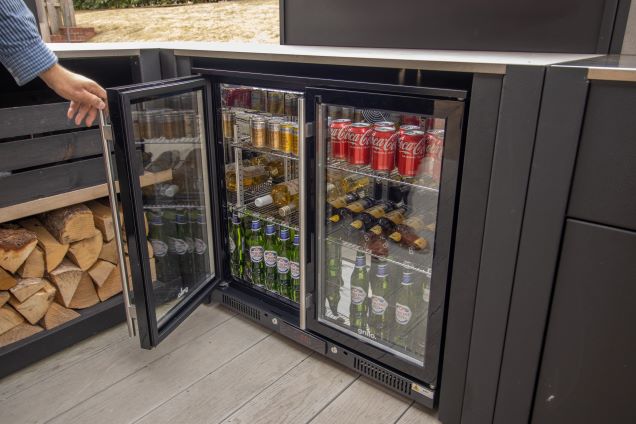 outdoor kitchen with person opening double fridge door