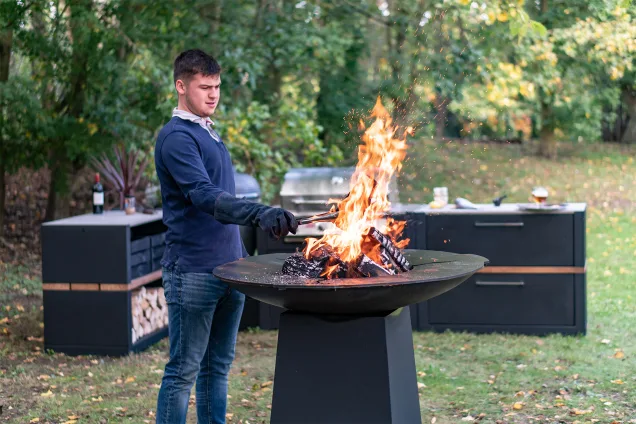 man using grillo chefs anvil in garden with kitchen in background