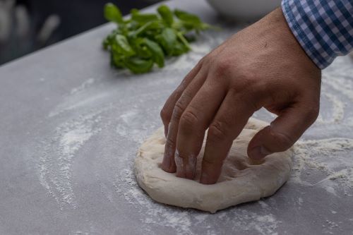 hand stretching out pizza dough
