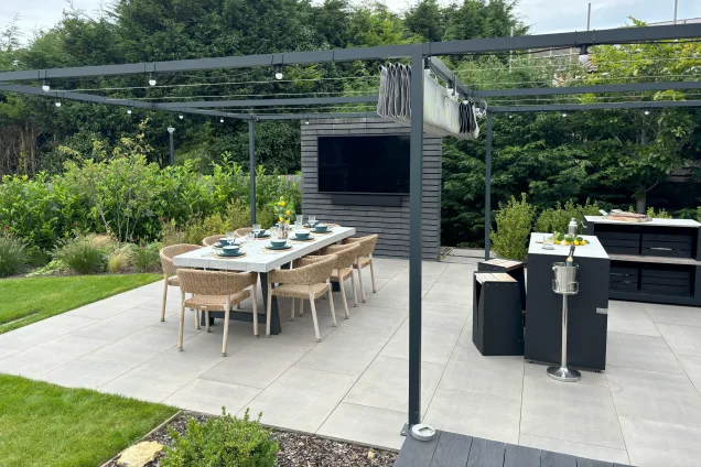 outdoor tv and dining table next to outdoor kitchen