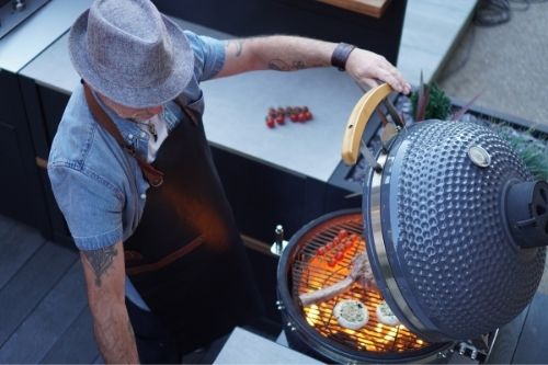 Man cooking on gusto charcoal bbq in grillo outdoor kitchen