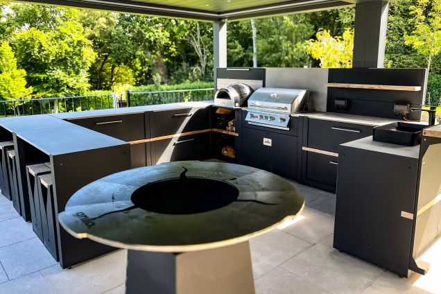 Outdoor kitchen in Runnymede, Surrey with large u shaped outdoor kitchen with chefs anvil in foreground