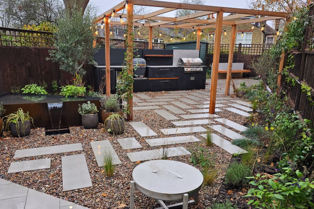 Outdoor kitchen in Dulwich in modern garden with pebble surrounded paving stones