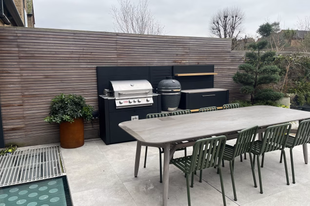 Outdoor kitchen in hammersmith on patio with large outdoor table and chairs