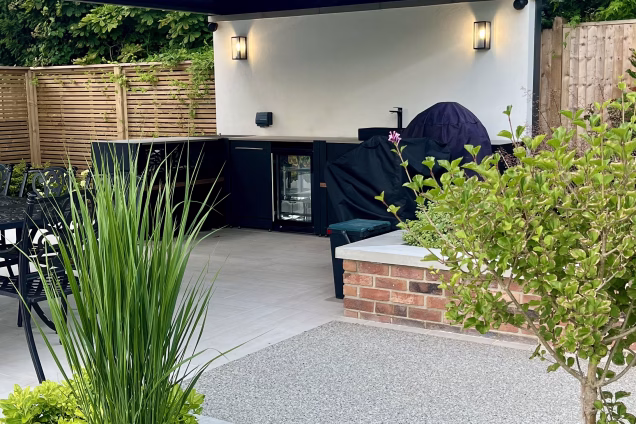 outdoor kitchen on patio under pergola and outdoor seating area on decking