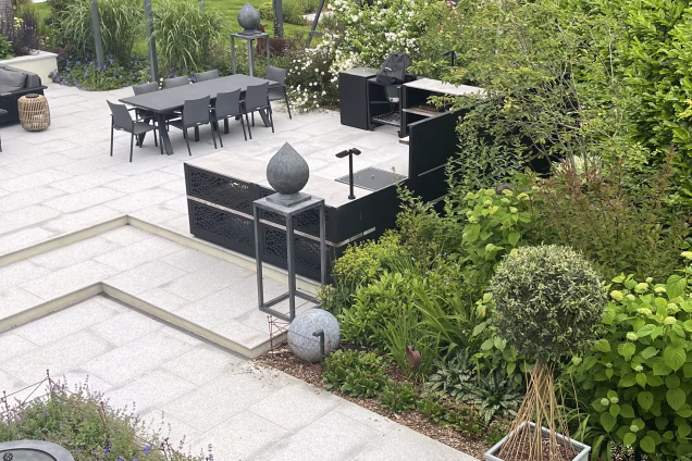 A photo from an upstairs window looking out along the landscaped gardens of a residential house in Cranleigh, Surrey. A Grillo outdoor kitchen is centre frame.
