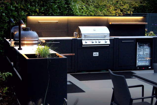 A telephoto image of an illuminated outdoor kitchen in Cranleigh