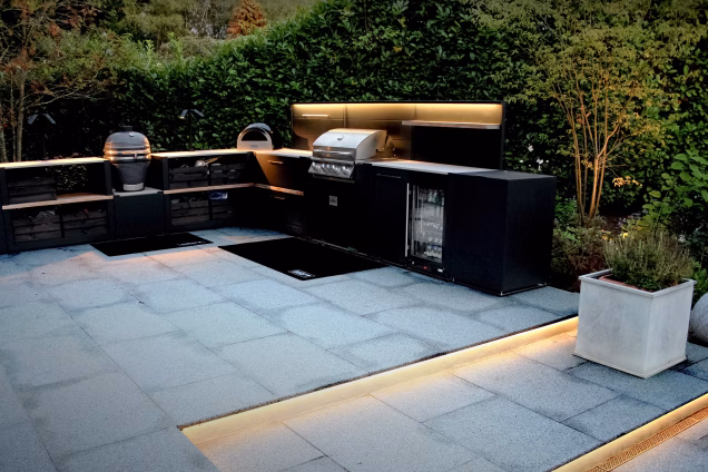 An outdoor kitchen in a residential garden in Cranleigh, UK, featuring custom garden lighting by Ornamental Garden Lighting.