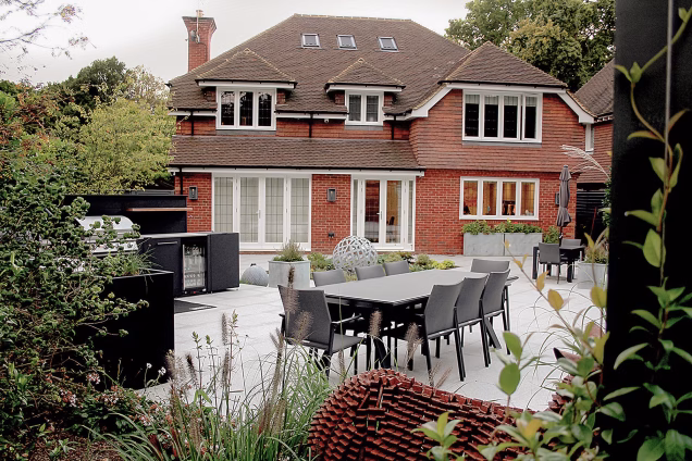 Back of a detached house in Cranleigh UK, with an outdoor kitchen and dining area in the foreground
