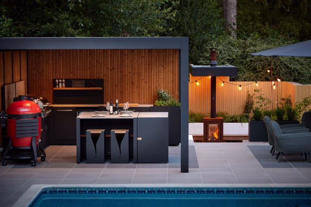 Outdoor kitchen next to a sunken suspended firepit area with hanging lights at dusk