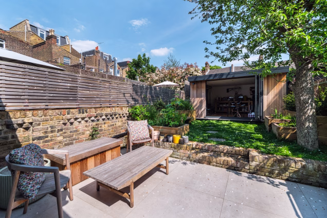 A small back garden in Stoke Newington, with stepping stones leading across the grass to a garden studio
