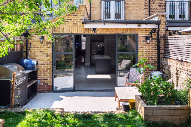 Looking towards the Crittall-style French doors at the back of a house in Stoke Newington, with a Grillo outdoor kitchen on the patio