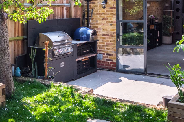 Outdoor kitchen with Delivita pizza oven and Bull gas grill in a garden in Stoke Newington, London in spring