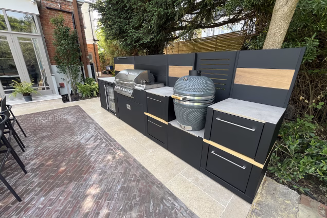Looking along an outdoor kitchen towards a large townhouse in an affluent area of London. Subtropical plants fill the borders