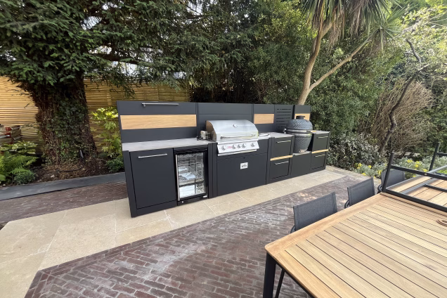 An outdoor kitchen in Richmond, London, set against a giant yew and a "Cordyline australis" cabbage palm