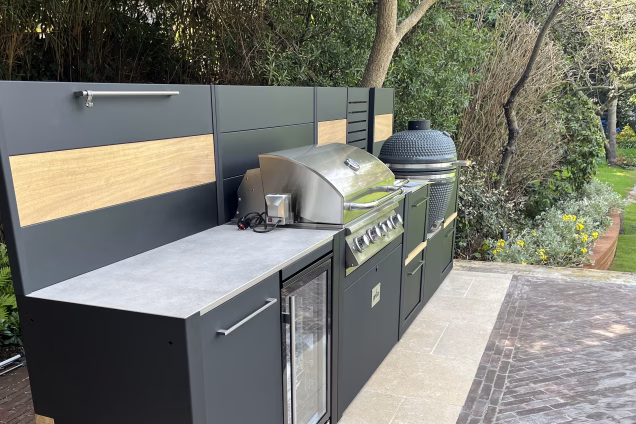 View looking along an outdoor kitchen in Richmond. The kitchen features a Bull Angus grill with rotisserie, a fridge and a Gusto kamado BBQ.