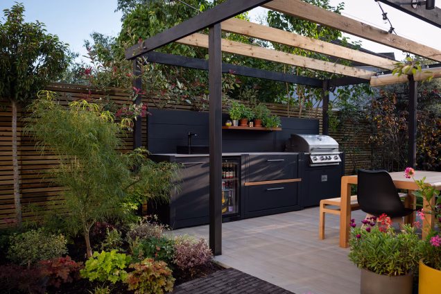 Outdoor kitchen in a garden with impressive planting, including Japanese maples and multicoloured heucheras