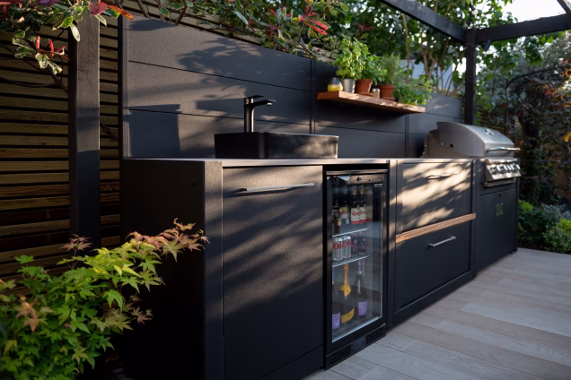 Dappled evening sunlight falls on a Grillo kitchen in a London garden