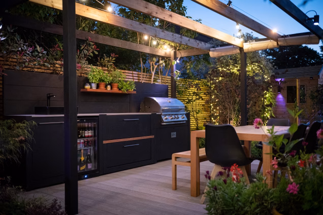 A Grillo outdoor kitchen under and open pergola in a garden in Lewisham, London, by Catherine Clancy Garden Design