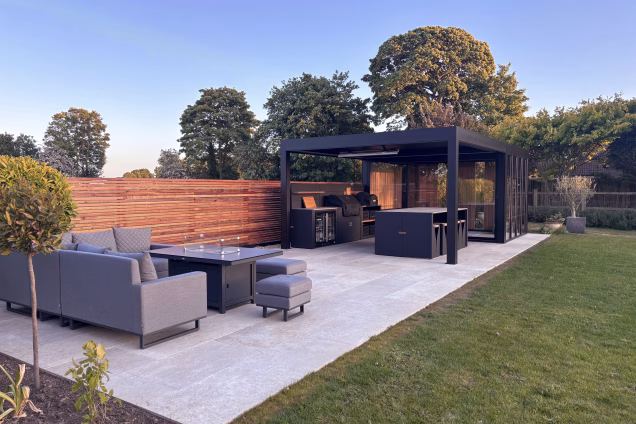 Outdoor living area with an outdoor kitchen, pergola and glazed seating area in the golden evening light