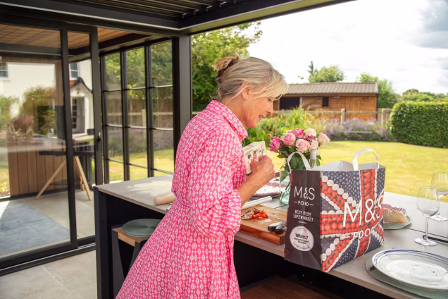 Sara looks into an M&S bag placed on the bar island in her outdoor kitchen in Attleborough