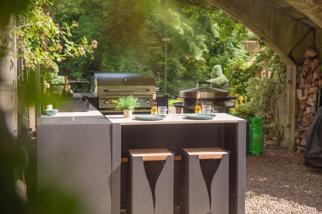 Looking along a Grillo outdoor kitchen towards the full-height, frameless glazing separating it from the garden views beyond