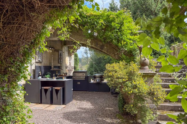 The Grillo outdoor kitchen under the arched double perron stairway leading down from the state rooms at a castle in the Scottish Borders
