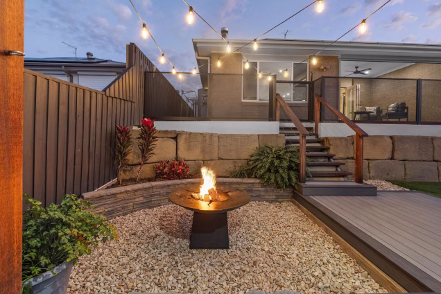 stoney firepit area with chefs anvil short in garden with decking