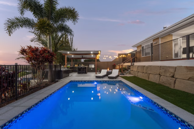 large pool in garden with decking and outdoor kitchen