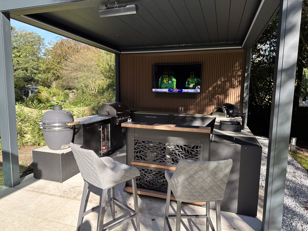 outdoor kitchen with gas and charcoal bbqs, standing bar table and stools, drinks station, fridge and storage units