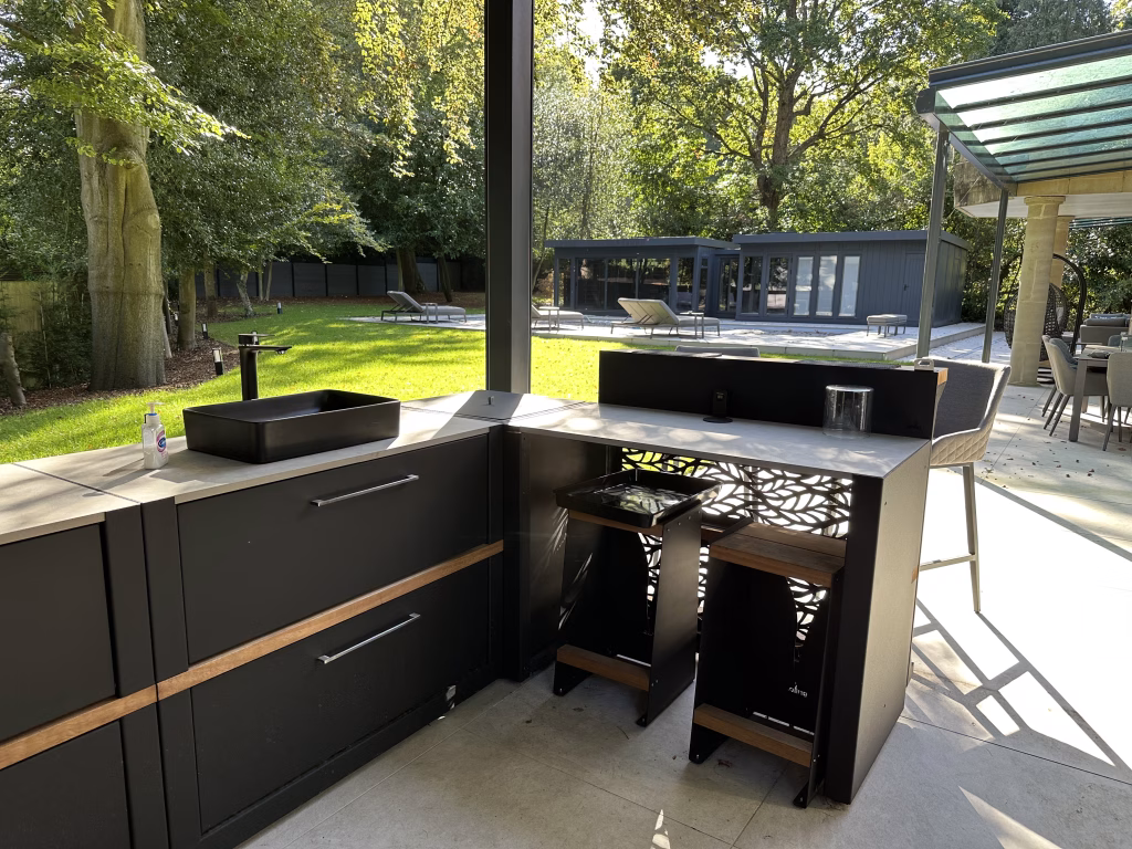 large garden with garden buildings, a pool and deck chairs and outdoor kitchen