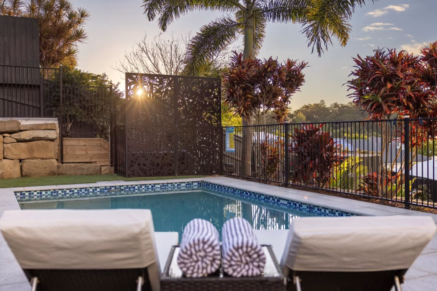 pool chairs on decking with pool in background