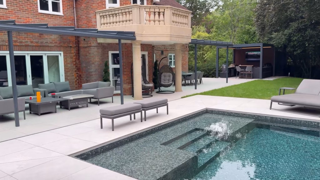 large pool with seating areas under pergola and outdoor kitchen under pergola