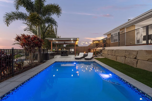 large pool in garden with decking and outdoor kitchen