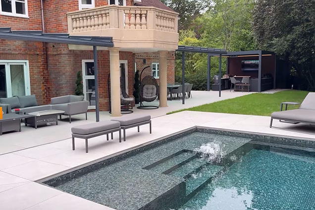 large pool with seating areas under pergola and outdoor kitchen under pergola