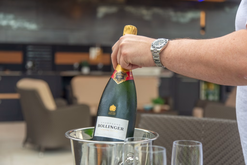 person holding champagne in front of grillo outdoor kitchen