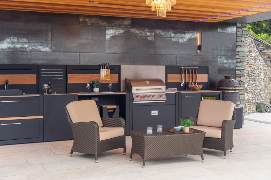 outdoor kitchen with charcoal and gas bbq, storage and seating under large covering over patio