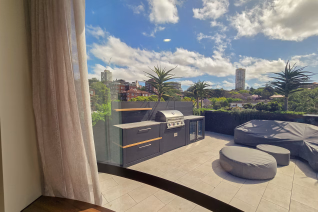 The view out of a curved window across a roof terrace in Double Bay