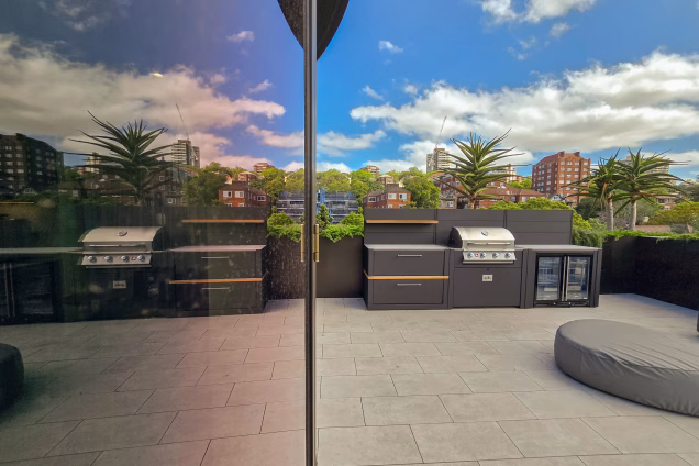 A Grillo kitchen is reflected in the glass of a penthouse-level Sydney office