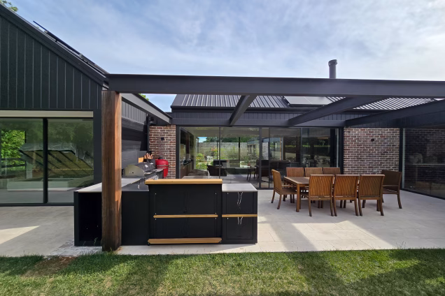The patio area of a contemporary house in Moss Vale NSW, featuring an outdoor kitchen, dining area and a heavy-duty I-beam decorative pergola