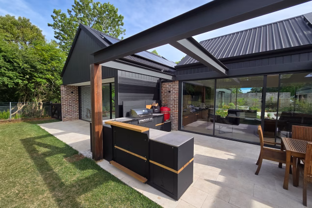 The view of a contemporary alfresco area in Moss Vale, with large glass sliding doors allowing a view through the house to the landscaped courtyard at the front