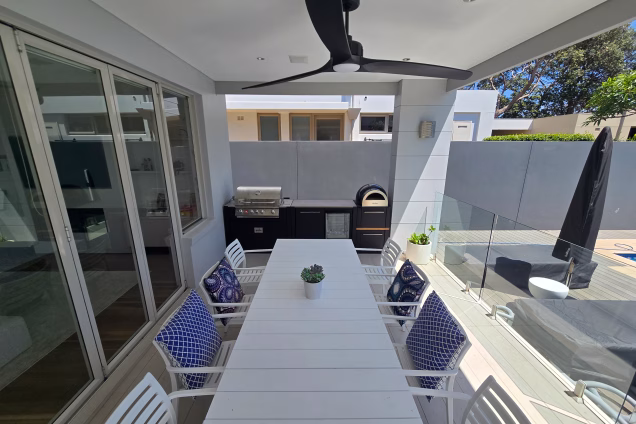View along a white dining table towards an outdoor kitchen in Sydney