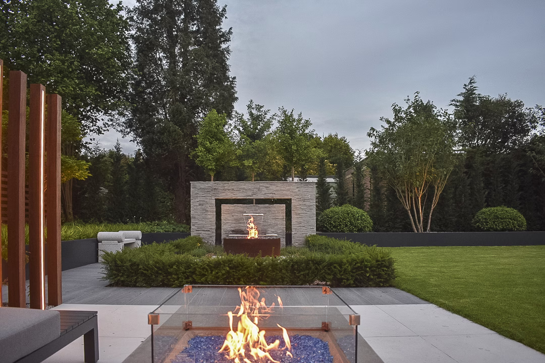 Seating area with a firepit over looking a stone water feature and planting