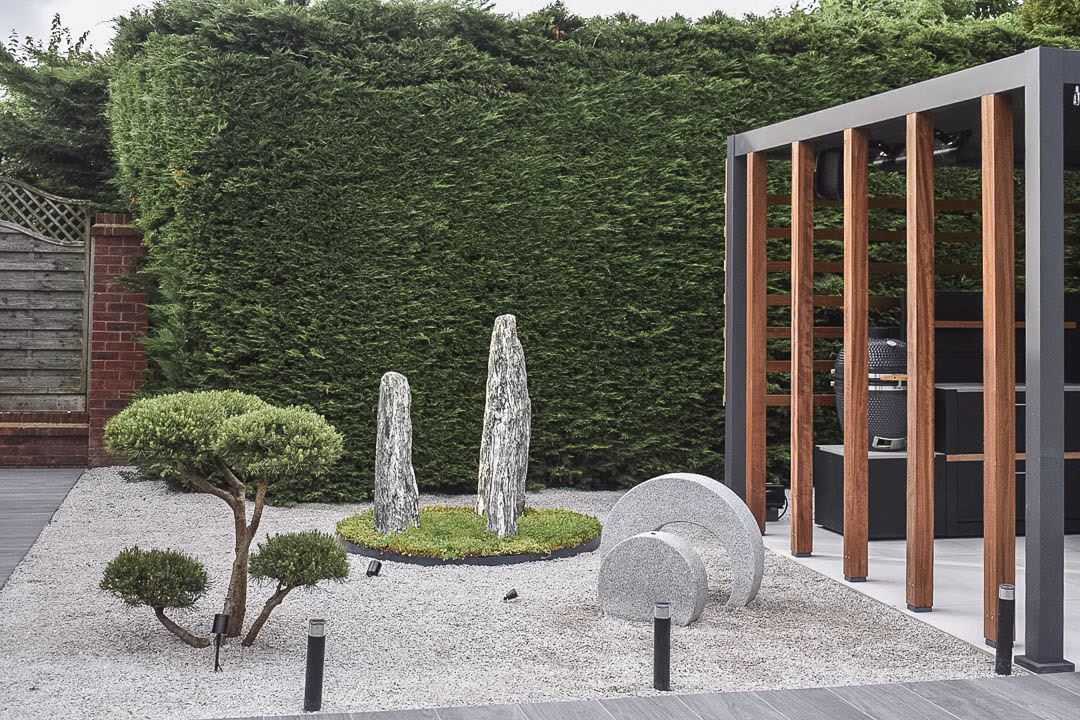 stone features in garden next to outdoor kitchen under pergola