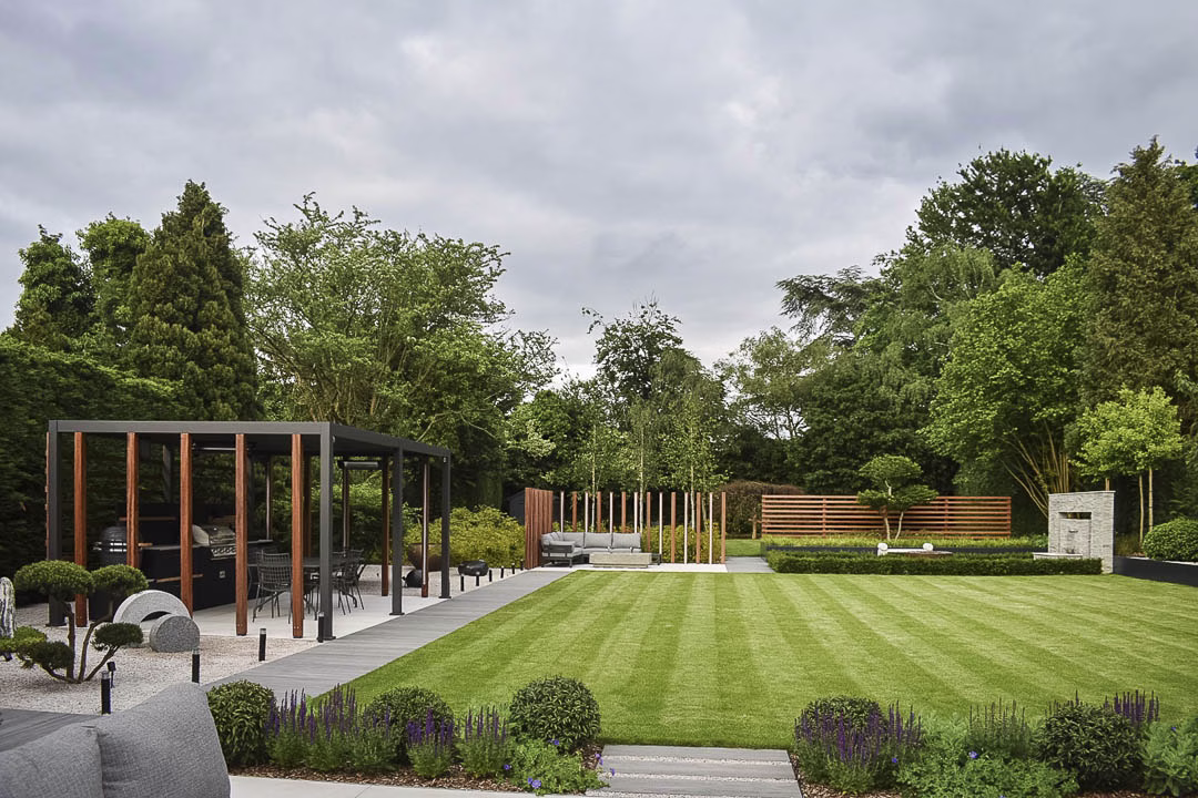 Beautiful garden with lawn stripes, an outdoor kitchen, seating areas and hedging
