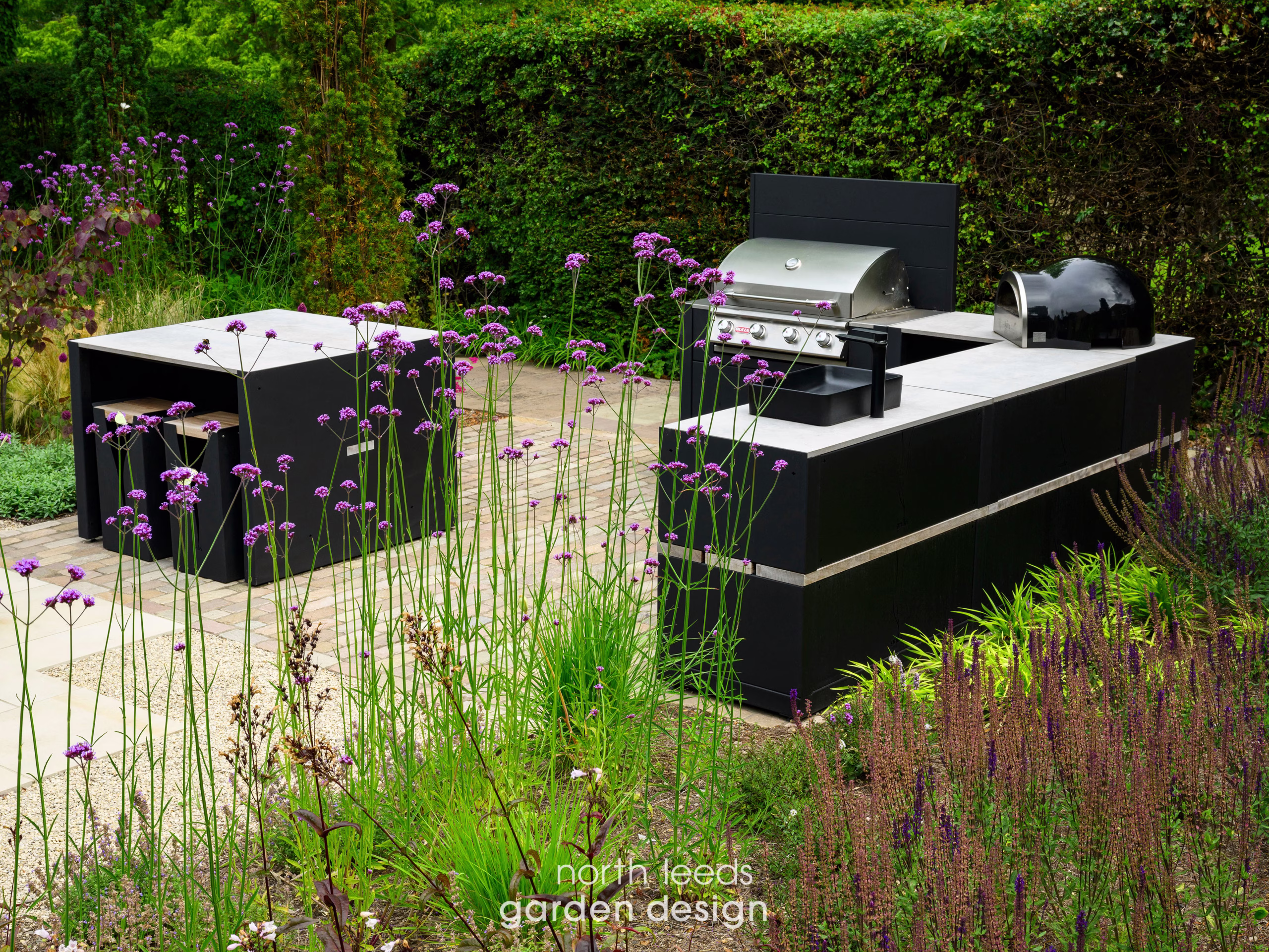 grillo kitchen with bar table and stools, storage, bbqs and sink, on paved patio