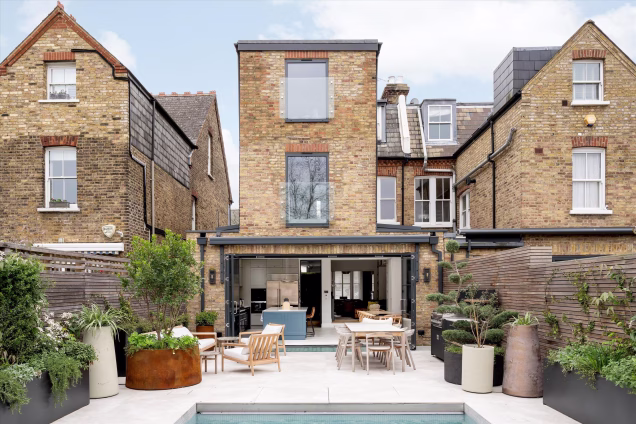 view of modern garden and house with outdoor kitchen and table and chairs