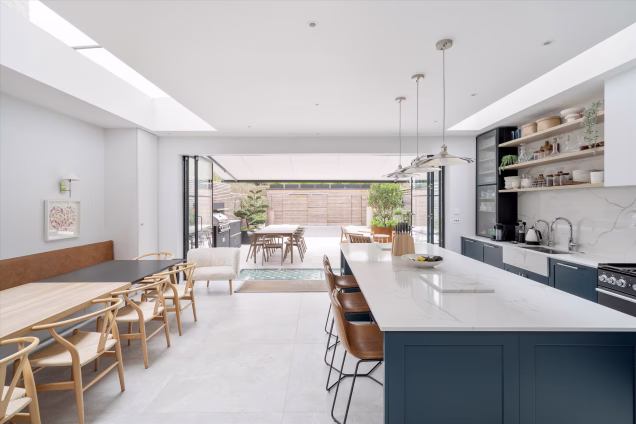 Photo of modern indoor kitchen with view out to hardscaped garden with outdoor kitchen